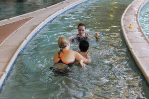 a picture of a child learning to swim with an instructor