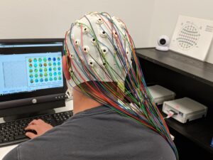 a picture of a man wearing an EEG cap with wires coming from it